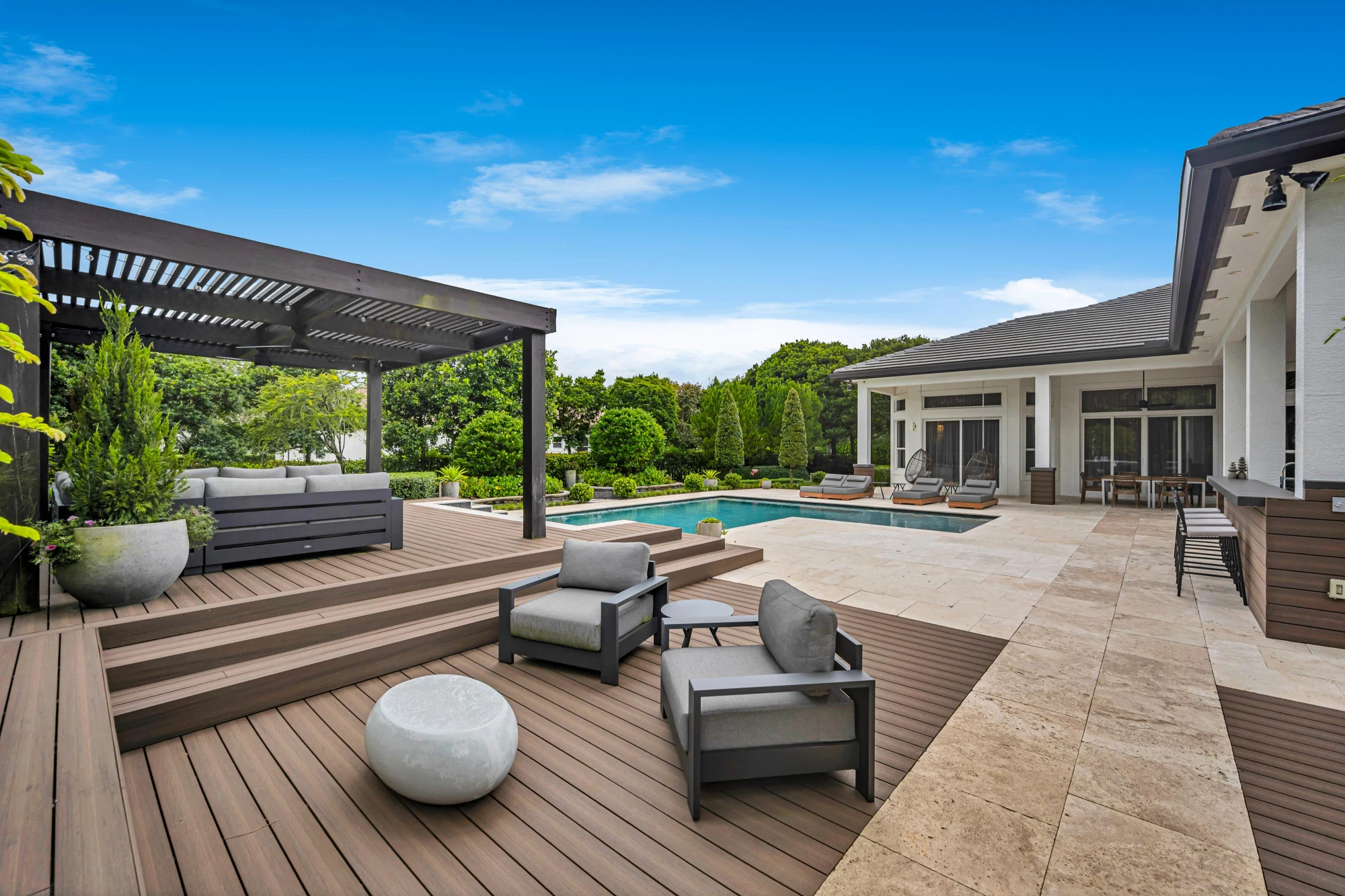 Pool deck with a louvered pergola and travertine terrace at the Long Lake Ranches estate, Davie, Florida, designed by Luxe Design Studios