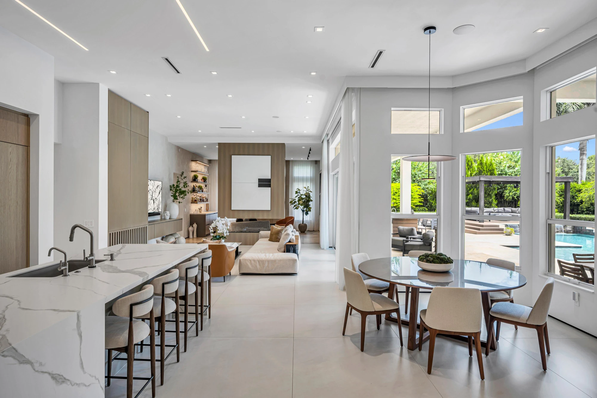 Kitchen and breakfast nook with a marble waterfall island in the Long Lake Ranches estate, Davie, Florida, designed by Luxe Design Studios